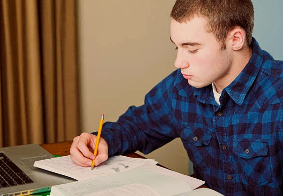 teen boy does homework close up